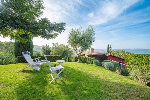 two chairs and a table in the grass at PODERE TORRICELLE 69B Pancole Gr, seaview infinity pool, jacuzzi, sauna, exclusive villa with 2 bedrooms for 4 - If you total 5 or 6 people there is an independent suite in main villa with private ensuite bathroom, kitchenette and garden dining area in Pancole