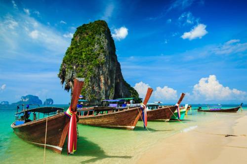 a group of boats on a beach with a mountain at Baan Santhiya Private Pool Villas - Free Tuk-Tuk Service to the Beach! in Ao Nang Beach