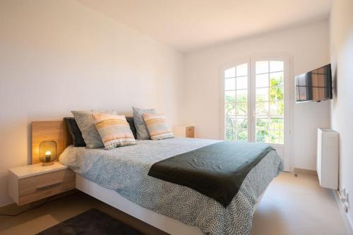 - une chambre blanche avec un lit et une fenêtre dans l'établissement Les Jardins de Provence • Beau Rivage • Proche mer, à Carqueiranne