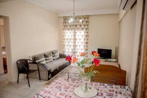 una sala de estar con una mesa con un jarrón de flores en SAVVAS en Néa Pláyia