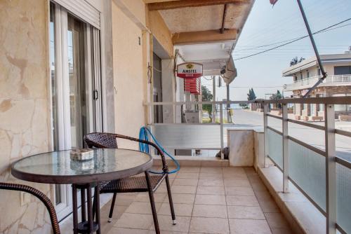 una mesa y sillas en un balcón con vistas a la calle en SAVVAS en Néa Pláyia