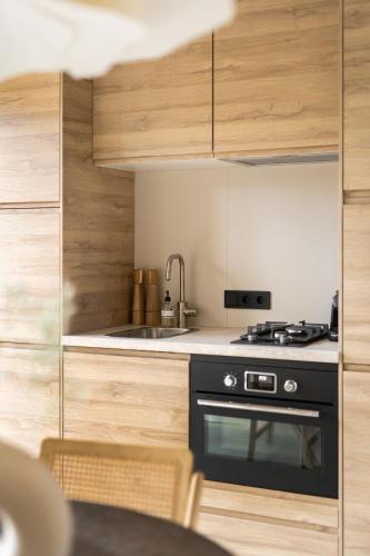 a kitchen with a black stove and wooden cabinets at Luxe tiny house STEC midden op de Veluwe in Nunspeet in Nunspeet