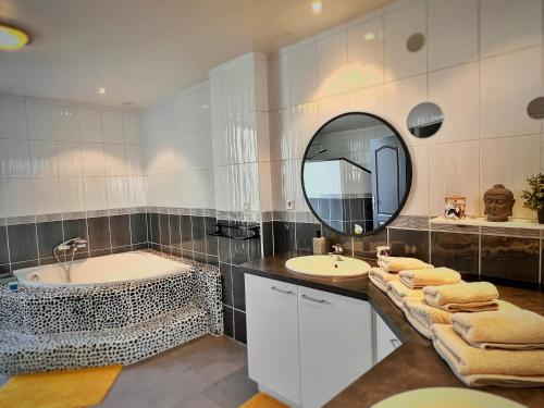 uma casa de banho com 2 lavatórios, uma banheira e um espelho. em Maison LAMARTINE - Plein Centre-Ville Avec Garage & Jeux em Saint-Claude