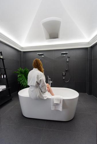 a woman sitting in a bath tub in a bathroom at Villa Las Mil Flores in Antigua Guatemala