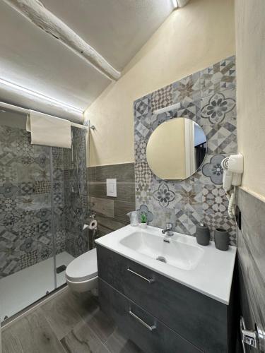 een badkamer met een wastafel, een toilet en een spiegel bij Olinad rooms in Castelbuono