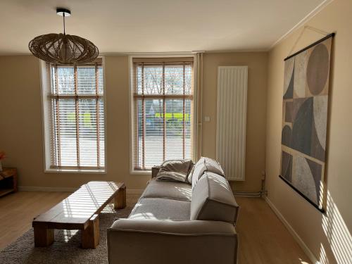 フラウウェンポルデルにあるDorpsdijk 49, Vrouwenpolder vakantieのソファと2つの窓があるリビングルーム