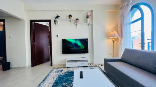 a living room with a couch and a flat screen tv at Newly furnished cozy ONE bed room Apartment 2 bathroom city view in Dubai