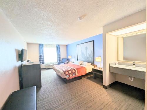 a hotel room with a bed and a sink at Super 8 by Wyndham Garland Rowlett East Dallas Area in Garland