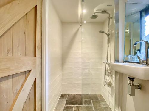 uma casa de banho com um chuveiro, um lavatório e um espelho. em The Chicken Shed em Cold Ashton