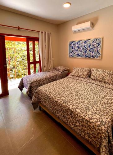 a bedroom with two beds and a window at Pousada Pipa Soul in Pipa