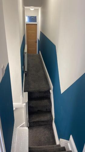 um corredor com uma escada com paredes azuis e uma porta em Anfield accomodation em Liverpool