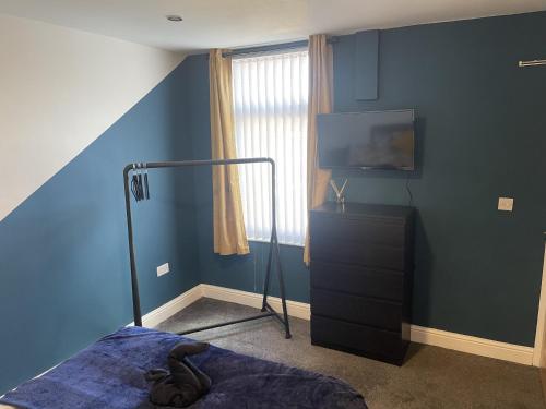 1 dormitorio con paredes azules, 1 cama y TV en Anfield accomodation, en Liverpool