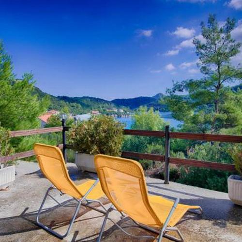 two chairs sitting on a patio with a view of a river at Apartments Bruna in Lastovo