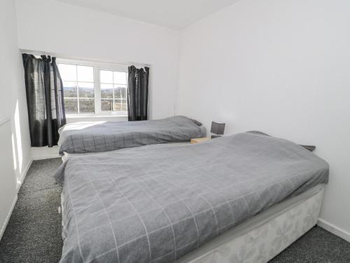 2 łóżka w sypialni z oknem w obiekcie Rhous w mieście Llanallgo