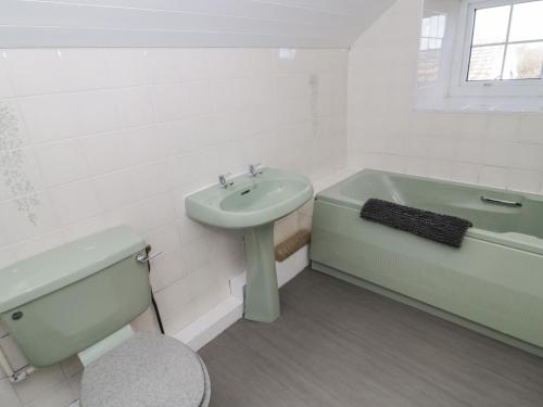 La salle de bains est pourvue d'un lavabo, d'une baignoire et de toilettes. dans l'établissement Rhous, à Llanallgo