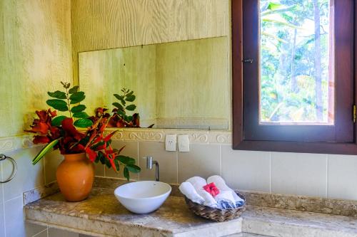 a bathroom with a sink and a vase with a mirror at Villa Beijaflor in Santo André