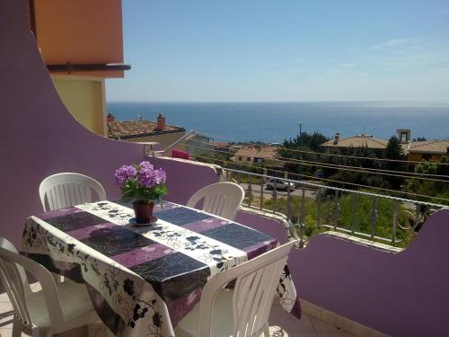 a table on a balcony with a view of the ocean at Casa Purple in Cala Gonone