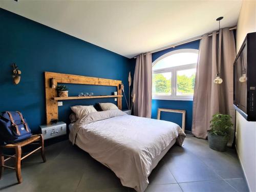une chambre avec un grand lit et un mur bleu dans l'établissement Climatisé & Cosy - T3 55 m2 parking à 2 mn de Lyon, à Caluire-et-Cuire