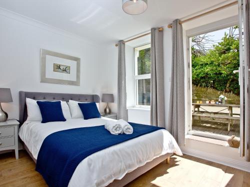 a bedroom with a blue and white bed and a window at 5 Devon Beach Court in Woolacombe