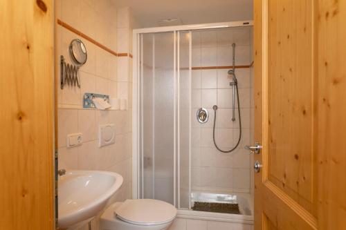 een badkamer met een douche, een toilet en een wastafel bij Kurbad und Landhaus Siass in Bad Kohlgrub