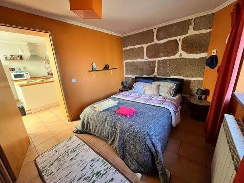 a bedroom with a bed with a stone wall at A comfortable rural space in beautiful gardens in Oliveira do Hospital