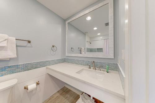 Baño blanco con lavabo y espejo en Luau Condos V en Destin