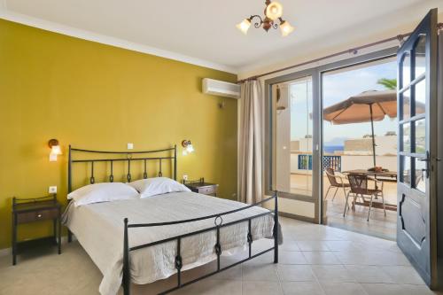 a bedroom with a bed and a balcony with a table at Sea Melody in Lefkos Karpathou