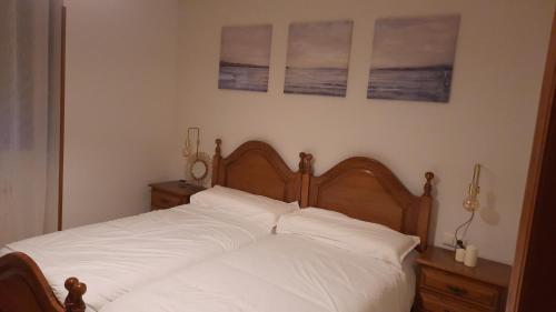 a bed with white sheets and two pictures on the wall at Gaiko Etxe Berri in Aizarnazábal