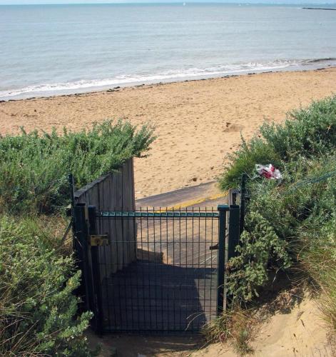 une porte ouverte sur une plage donnant sur l'océan dans l'établissement Studio-terrasse 3* bord de mer Châtelaillon plage, à Châtelaillon-Plage