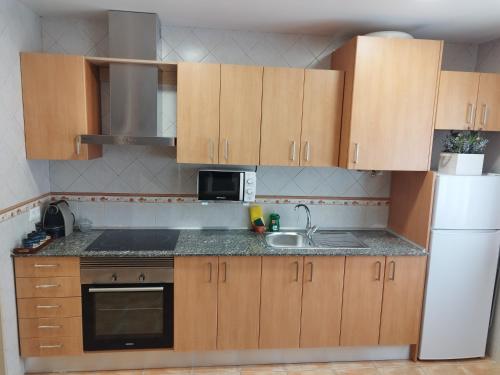 a kitchen with wooden cabinets and a sink and a refrigerator at Apartamento Torre Sancho in Valderrobres
