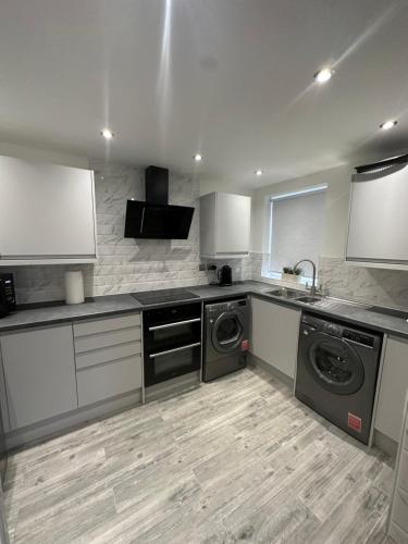 a kitchen with a sink and washing machines in it at Watford Road House Liverpool in Liverpool