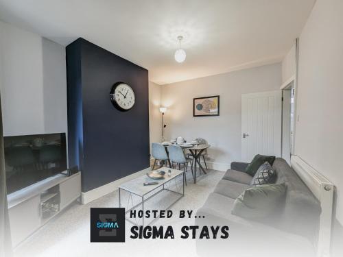 a living room with a couch and a clock on a wall at Derrington House - By Sigma Stays in Crewe