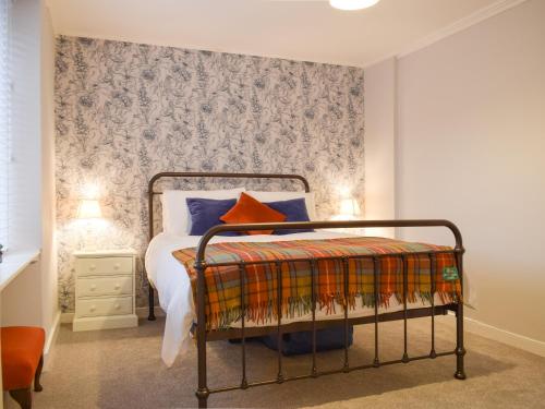 a bedroom with a bed with a patterned wall at Cromwell Cottage in Burntisland