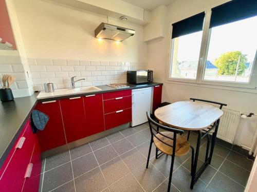 une cuisine avec des placards rouges et une table en bois dans l'établissement Giena - SILS, à Caen