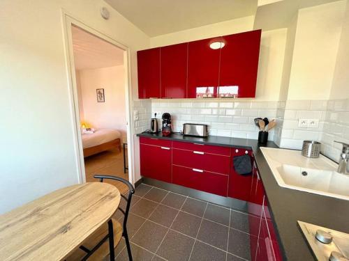 uma cozinha com armários vermelhos, uma mesa e um lavatório em Giena - SILS em Caen