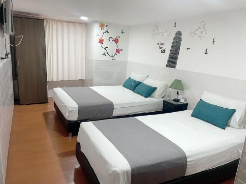 a hotel room with two beds with blue pillows at Casa Hotel Quinta Real in Bogotá