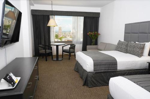 a hotel room with a bed and a couch and a table at Hotel San Marcos Grand in Culiacán