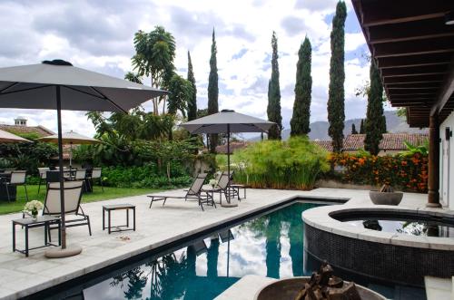 een patio met stoelen en parasols naast een zwembad bij Villa Las Mil Flores in Antigua Guatemala