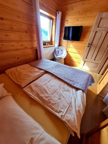 a bedroom with a bed in a wooden room at Gorczańska Chata z tarasem widokowym in Poręba Wielka