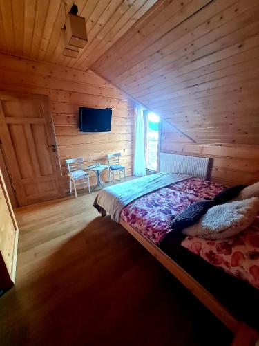 a bedroom with a bed in a wooden cabin at Gorczańska Chata z tarasem widokowym in Poręba Wielka
