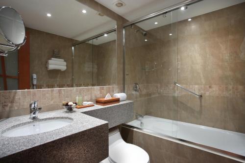 y baño con lavabo, ducha y bañera. en El Dorado Hotel, en Cuenca
