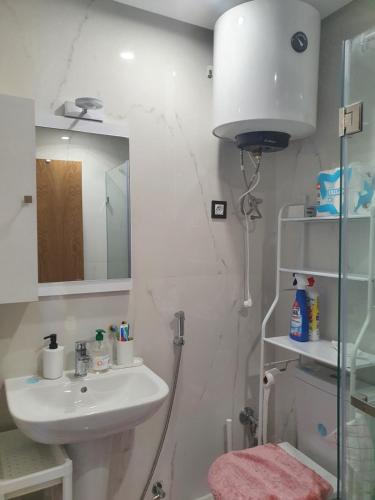 a white bathroom with a sink and a mirror at Superbe appartement pieds dans l'eau Mehdia in Kenitra