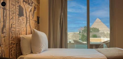 a bedroom with a window with a view of the pyramids at Giza Pyramids View Inn in Cairo