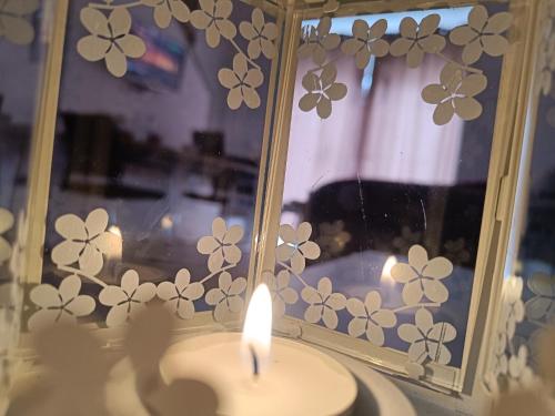 a candle in front of a window with a mirror at Korzo Apartment in Bijelo Polje
