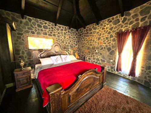 a bedroom with a wooden bed with a red blanket at Villas Gasconia in Antigua Guatemala