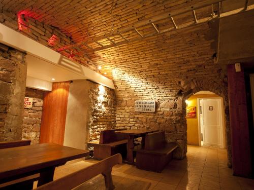 a restaurant with wooden tables and a brick wall at Hôtel le Grillon in Strasbourg