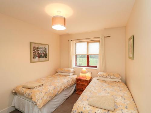 two beds in a room with a window at Grove Cottage in Whitby