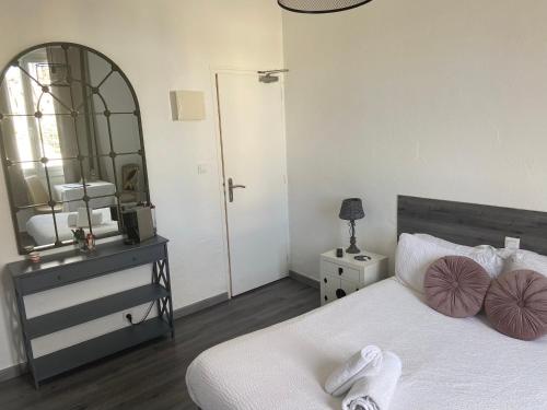 a bedroom with a white bed and a mirror at Hôtel Restaurant La Plage in Saint-Louis-du-Rhône