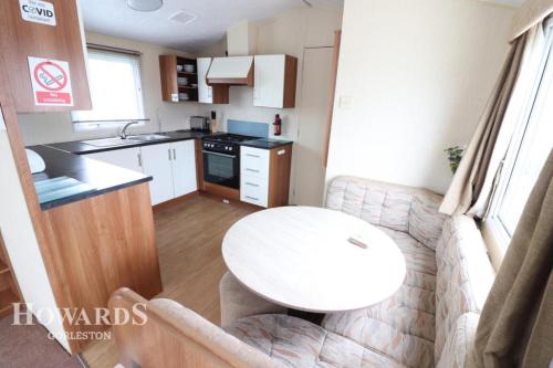 a small kitchen with a white table in a caravan at 3 bed caravan Norfolk near the coast in Belton