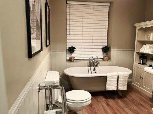 a bathroom with a white tub and a toilet at Wellington Cottage in Ilkley